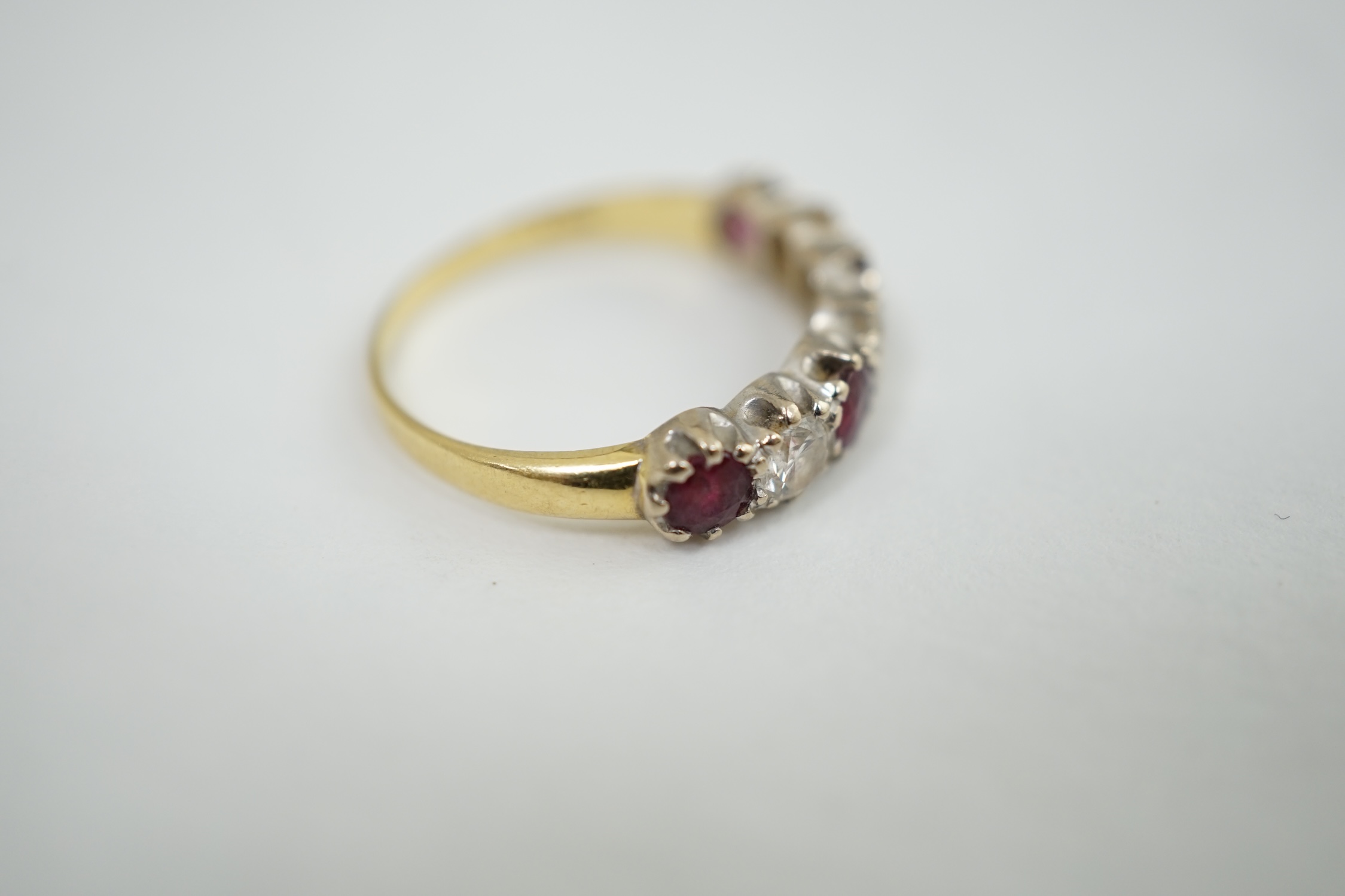 An 18ct yellow and white gold three stone diamond and four stone ruby set half hoop ring